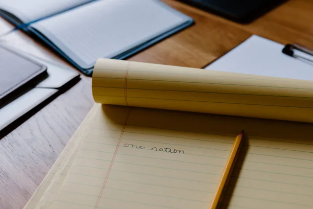 Close-up of a handwritten note on a yellow notepad, featuring the phrase 'one nation' with a pencil nearby. Reporting resources tools are mostly free: what a dated record still does