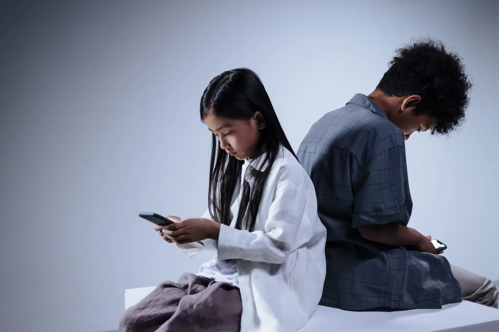 Two teenagers engrossed in their smartphones, highlighting digital connection and youth lifestyle. Parental controls changes: one audit for devices and apps