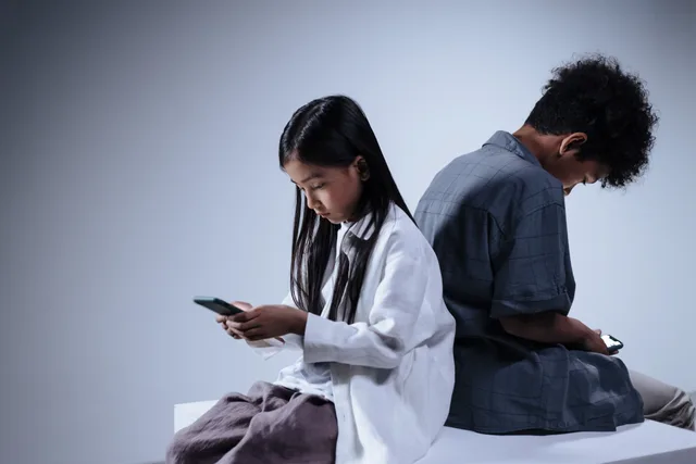 Two teenagers engrossed in their smartphones, highlighting digital connection and youth lifestyle. Parental controls changes: one audit for devices and apps
