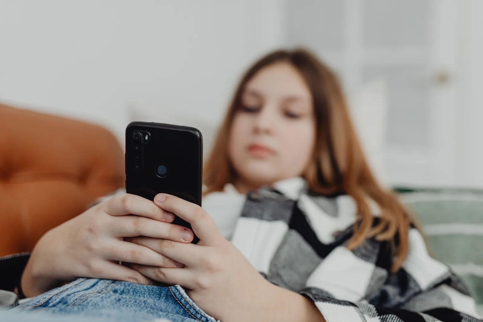 Teenage girl using smartphone while relaxing on a sofa, depicting leisure and connectivity. Reporting resources guide: follow up on a report